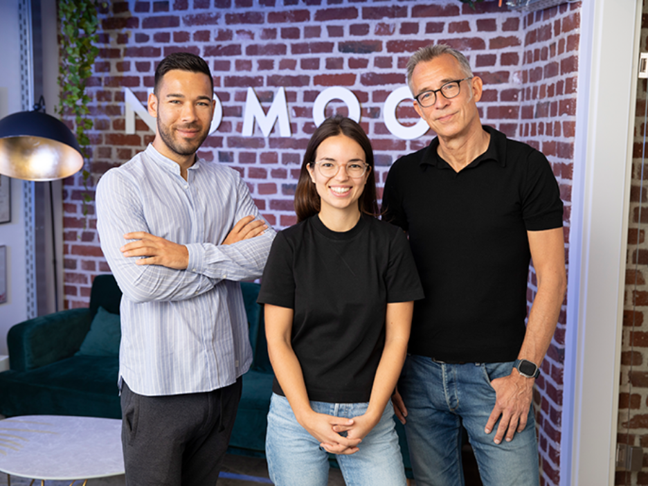 Drei Personen stehen nebeneinander vor einer Backsteinwand