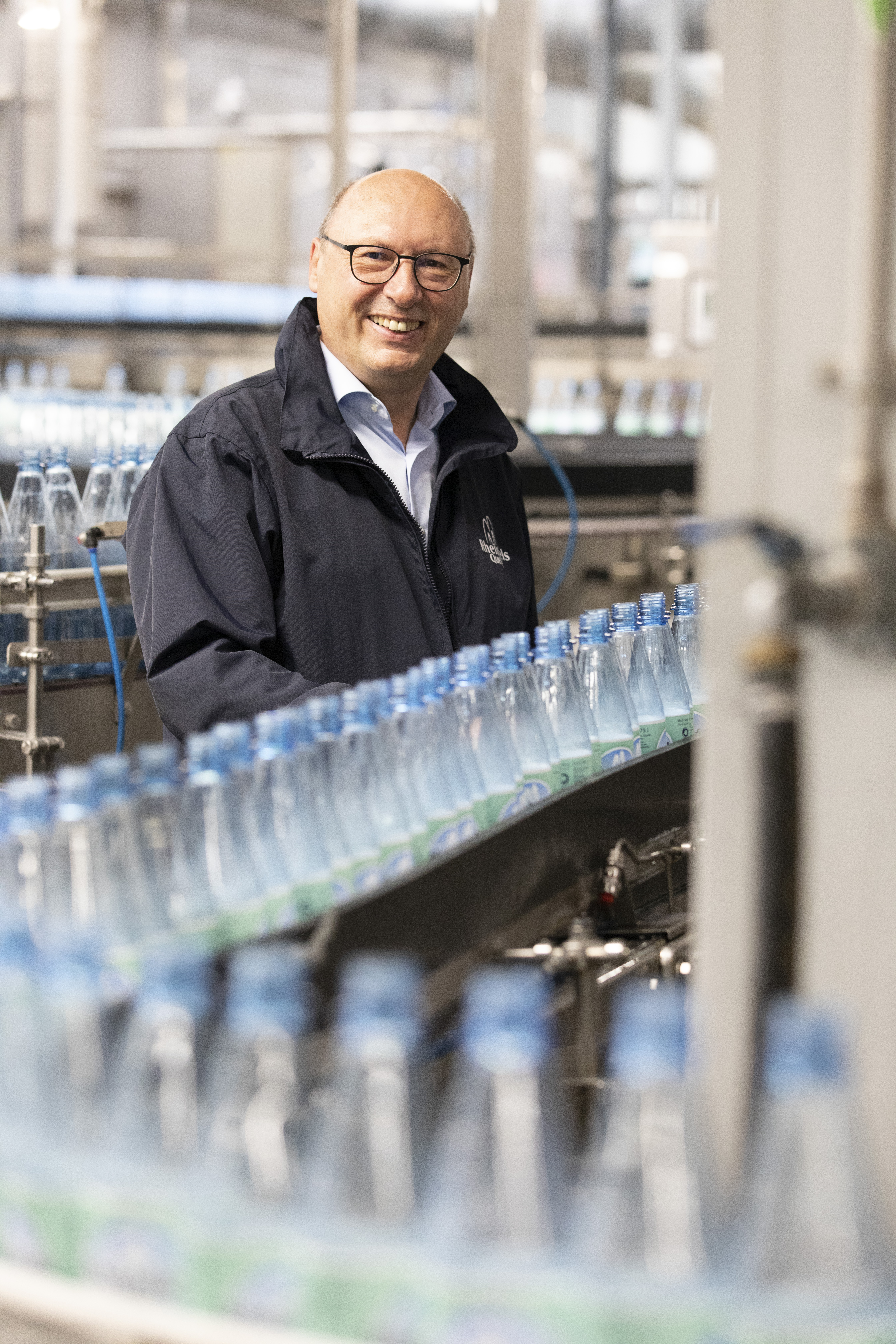 Ein Mann steht vor einer Abfüllanlage für Mineralwasserflaschen.