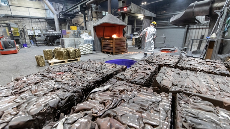 Mann in silbernem Hitzeanzug steht an Metallschmelze