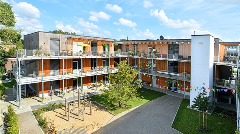 Innenhof des Wohnprojekts TRIALOG in Hilden mit Spielplatz und bunten Fahnengirlanden.