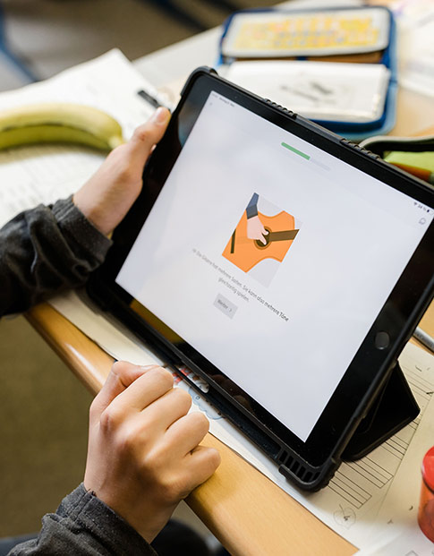 Ein Schüler bedient einen Tablet-Computer mit geöffneter Lern-App