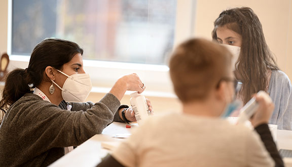 Kinder im MANUS Kinder- und Jugendzentrum basteln zusammen mit einer Mitarbeiterin.