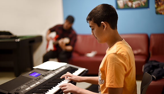 Eine Junge im MANUS Kinder- und Jugendzentrum spielt Keyboard.