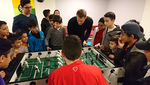 Fußballprofi Manuel Neuer spielt mit Kindern am Kicker.