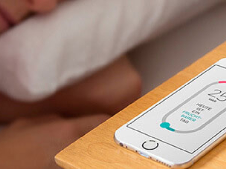 Auf einem Nachttisch liegt ein Smartphone, auf dem Display ist die trackle-App zu sehen.