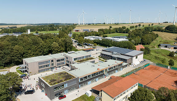 Großes Schulgelände mit mehreren Gebäuden mit Dachbegrünung und Solarpanels