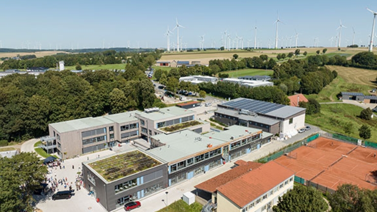 Großes Schulgelände mit mehreren Gebäuden mit Dachbegrünung und Solarpanels