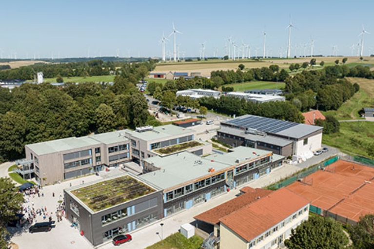 Großes Schulgelände mit mehreren Gebäuden mit Dachbegrünung und Solarpanels