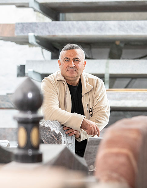 Hamid Osman lehnt an einem Grabstein vor großen Marmorplatten