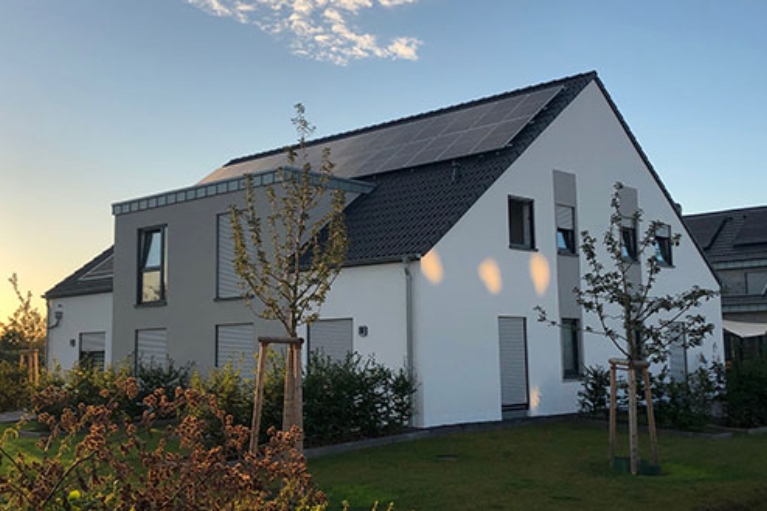 Ein Wohnhaus mit Solaranlagen auf dem Dach und Garten