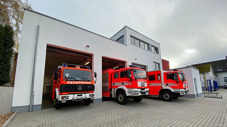 Drei Feuerwehrautos stehen in den Einfahrten eines Feuerwehrhauses