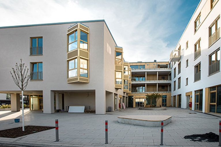 Ein heller Gebäudekomplex mit Flachdach und spitzen Fenstern