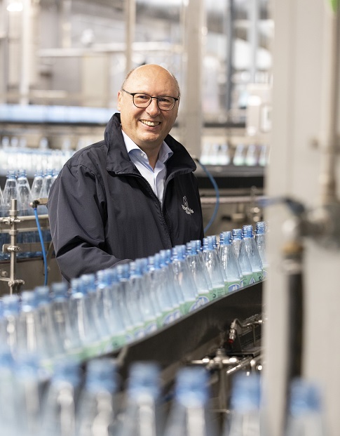 Ein Mann steht vor einer Abfüllanlage für Mineralwasserflaschen.