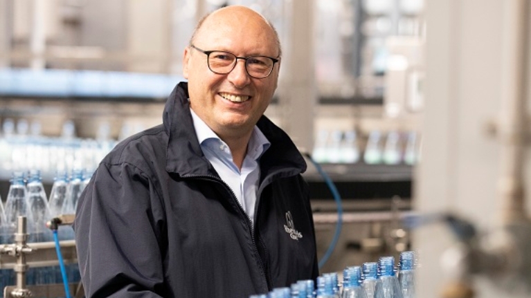 Ein Mann steht vor einer Abfüllanlage für Mineralwasserflaschen.