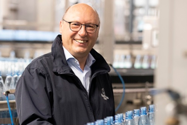 Ein Mann steht vor einer Abfüllanlage für Mineralwasserflaschen.