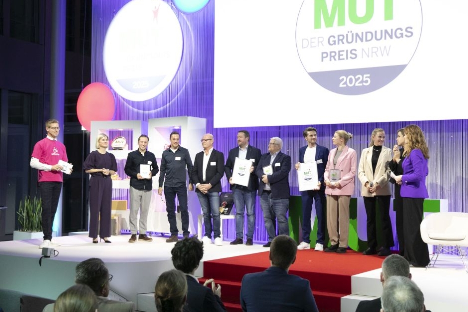 Die Gewinner von MUT - DER GRÜNDUNGSPREIS NRW 2025 bei der Preisverleihung mit den Moderatoren auf der Bühne