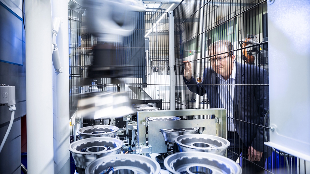 Jürgen Bischopink vom Automobilzulieferer Fischer und Kaufmann betrachtet durch einen Zaun die Produktion von Metallbauteilen.