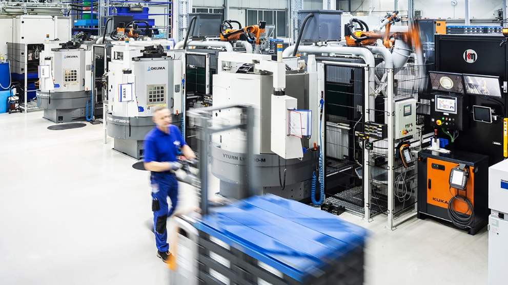 Halle des Automobilzulieferers Fischer und Kaufmann mit technischen Anlagen, ein Mann fährt mit einem Hubwagen.