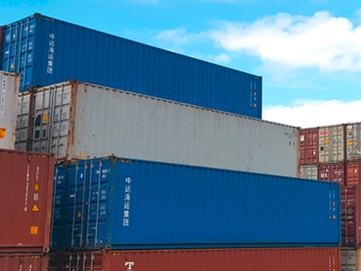 Mehrere verschiedenfarbige Schiffscontainer, die in einem Hafen gestapelt sind.