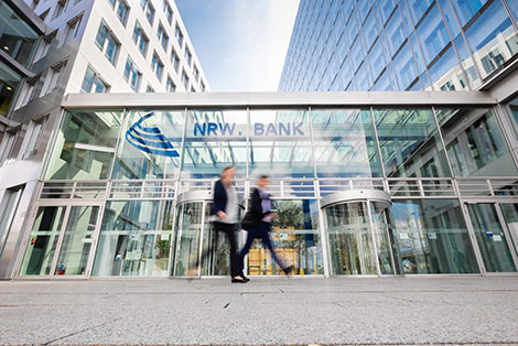Zwei Menschen vor dem gläsernen Eingangsbereich der NRW.BANK-Zentrale in Düsseldorf
