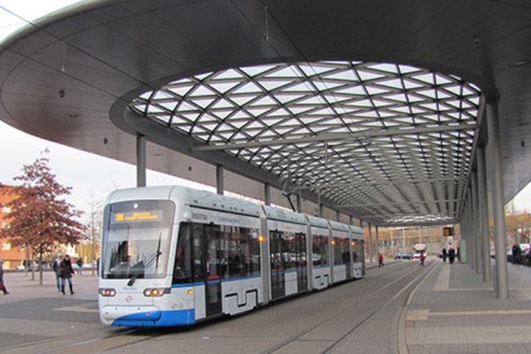 Weiße Straßenbahn der BOGESTRA unter dem modernen Dach einer Haltestelle