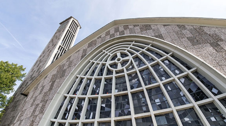 Graue Steinfassade der Martinskirche in Beckum mit kunstvoll geschwungenen Fenstern