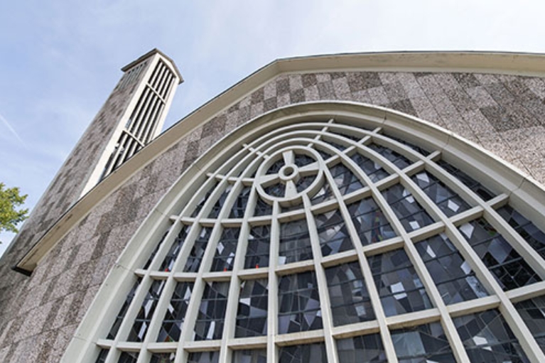 Graue Steinfassade der Martinskirche in Beckum mit kunstvoll geschwungenen Fenstern