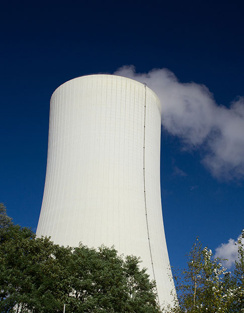 Der große, dampfende Schornstein des Gas- und Dampfkraftwerks Herne 6 vor blauem Himmel