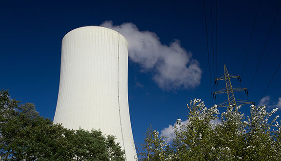 Der große, dampfende Schornstein des Gas- und Dampfkraftwerks Herne 6 vor blauem Himmel