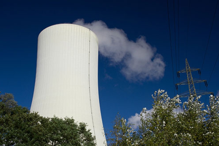 Der große, dampfende Schornstein des Gas- und Dampfkraftwerks Herne 6 vor blauem Himmel