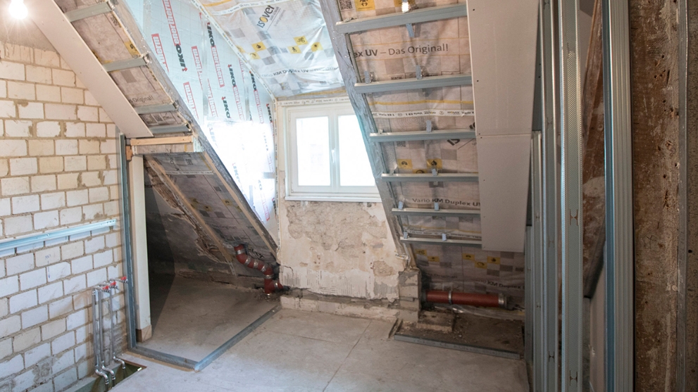 Ausschnitt eines Dachbodens im Rohbauz, man sieht die Dämmung und ein Fenster.