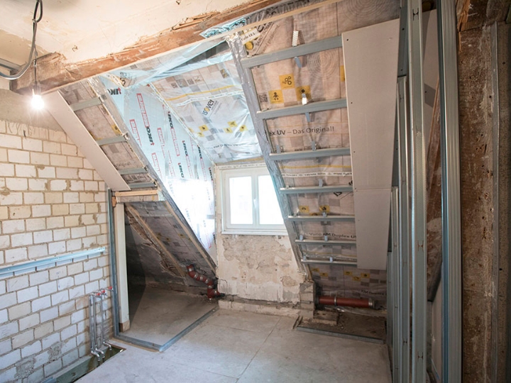 Ausschnitt eines Dachbodens im Rohbauz, man sieht die Dämmung und ein Fenster.