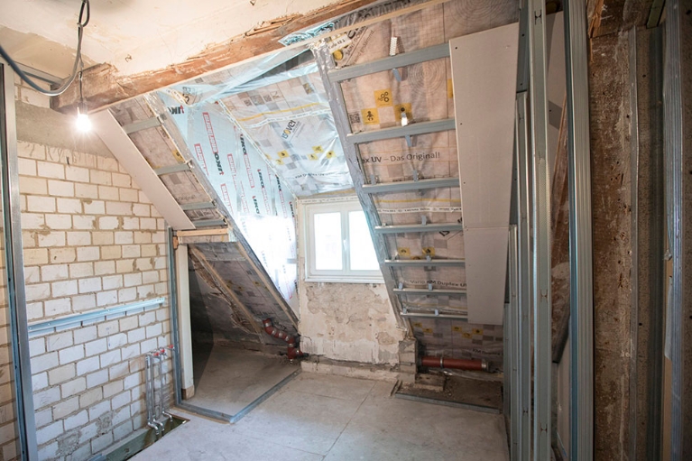 Ausschnitt eines Dachbodens im Rohbauz, man sieht die Dämmung und ein Fenster.