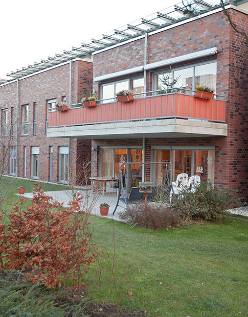 Reihenhäuser mit roter Backsteinfassade, davor Terrassen und Gärten