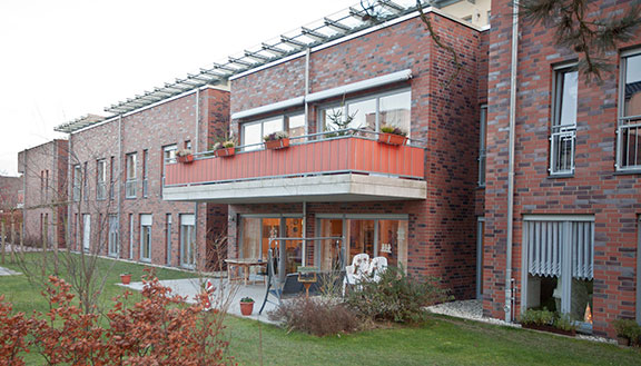 Reihenhäuser mit roter Backsteinfassade, davor Terrassen und Gärten