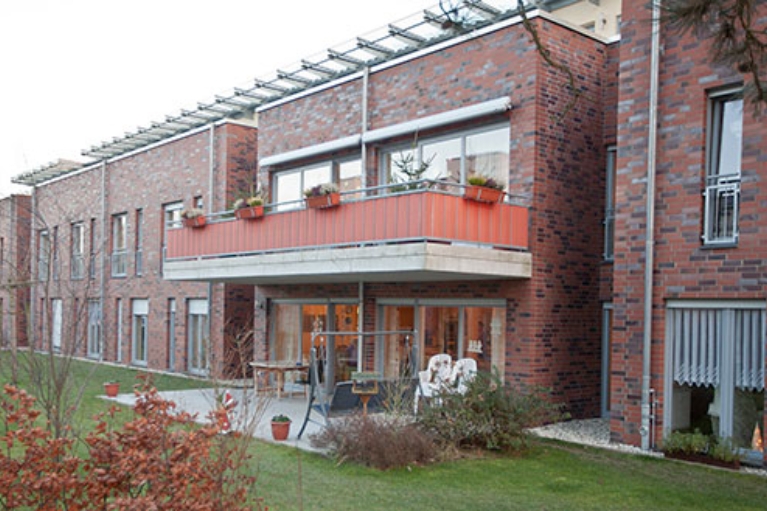 Reihenhäuser mit roter Backsteinfassade, davor Terrassen und Gärten