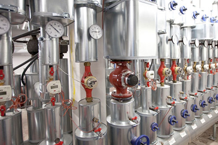 Moderne, silbern glänzende Heizungsanlage in einem Keller mit Ventilen und Messanzeigen