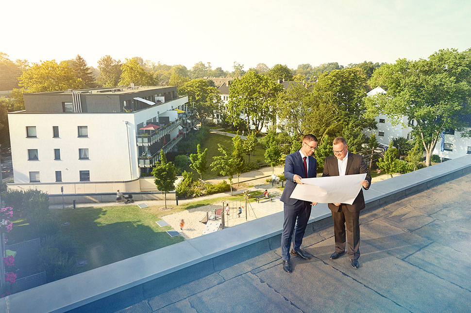 Das Bild zeigt die Vorstände der GWG Neuss Stefan Zellnig und Ulrich Brombach auf einem Hausdach. Sie planen neuen Wohnungsbau mit öffentlicher Förderung über die NRW.BANK.