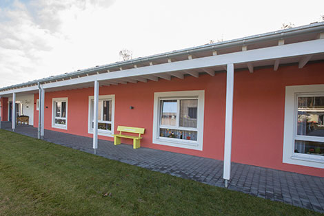 Eingeschossiges, rotes Gebäude des Seniorenzentrums Süssendell in Stolberg, davor eine gelbe Bank und eine Wiese