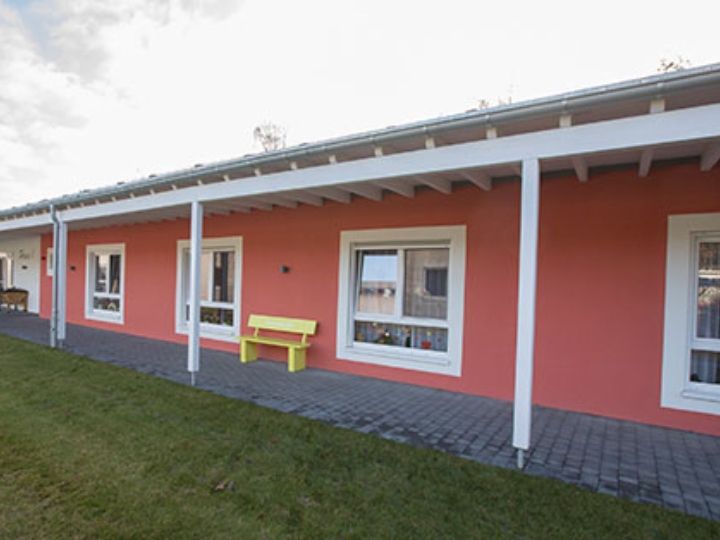 Eingeschossiges, rotes Gebäude des Seniorenzentrums Süssendell in Stolberg, davor eine gelbe Bank und eine Wiese