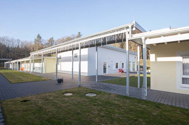 Eingeschossiger Gebäudekomplex des Seniorenzentrums Süssendell in Stolberg, dazwischen gepflasterte Weg und Grünstreifen