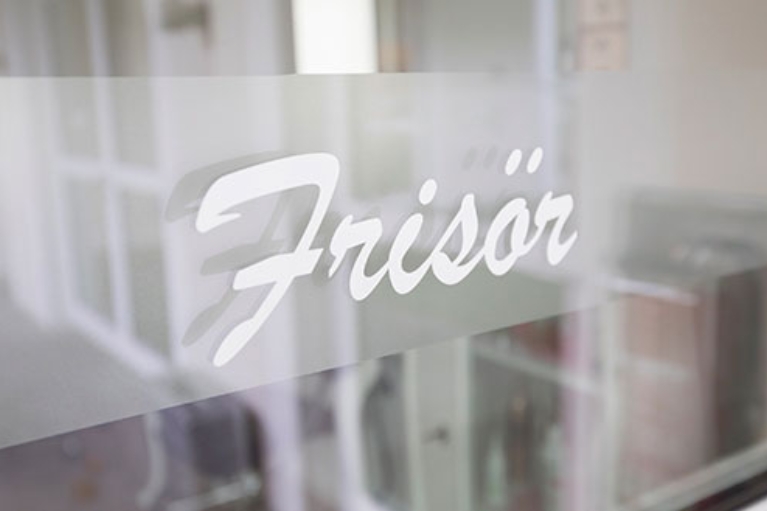 Glasscheibe eines Ladenlokals mit der Aufschrift Frisör