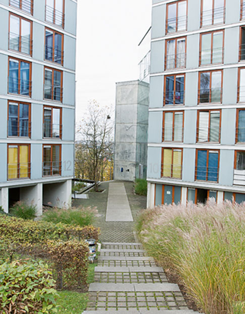 Ein Weg führt zwischen zwei Gebäuden eines Studentenwohnheims hindurch, seitlich des Weges Grünflächen.