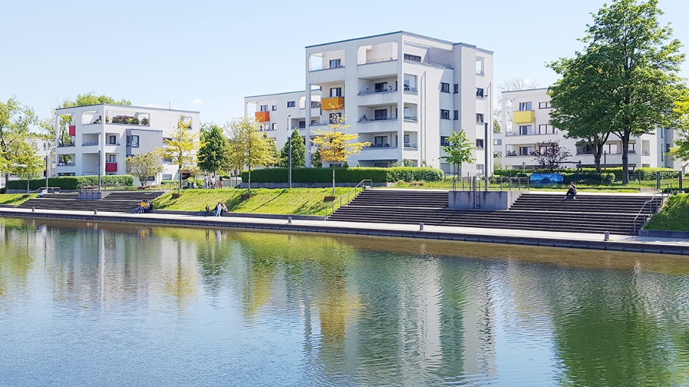 Der Niederfeldsee in Essen-Altendorf mit umliegender Parkanlage, mehreren Passanten und einem Wohnquartier