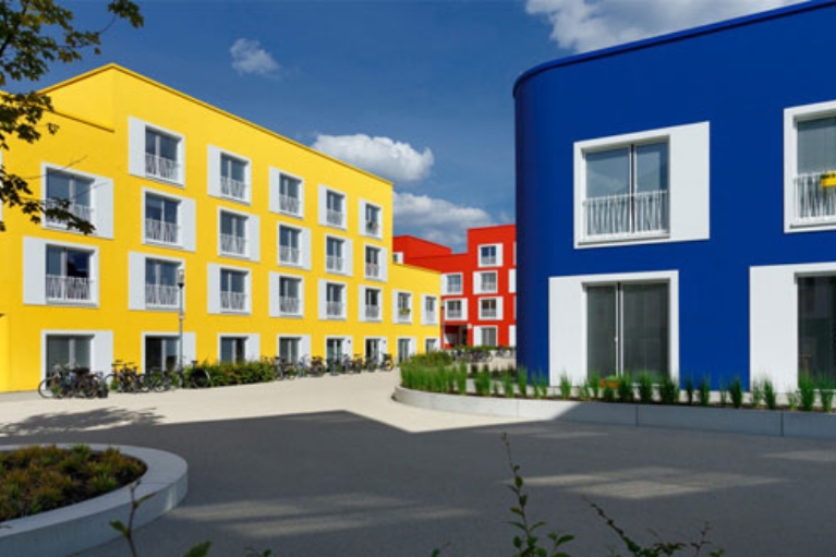 Gebäude einer Passivhaussiedlung für Studierende mit leuchtend gelb-rot-blauer Fassade