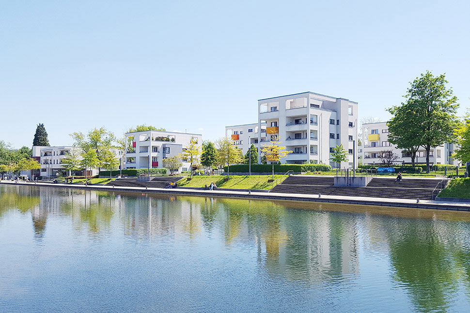 Der Niederfeldsee in Essen-Altendorf mit umliegender Parkanlage, mehreren Passanten und einem Wohnquartier