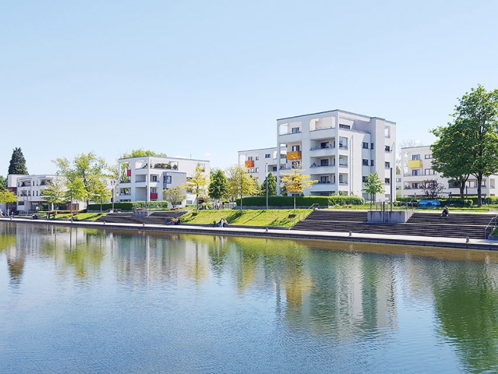 Der Niederfeldsee in Essen-Altendorf mit umliegender Parkanlage, mehreren Passanten und einem Wohnquartier