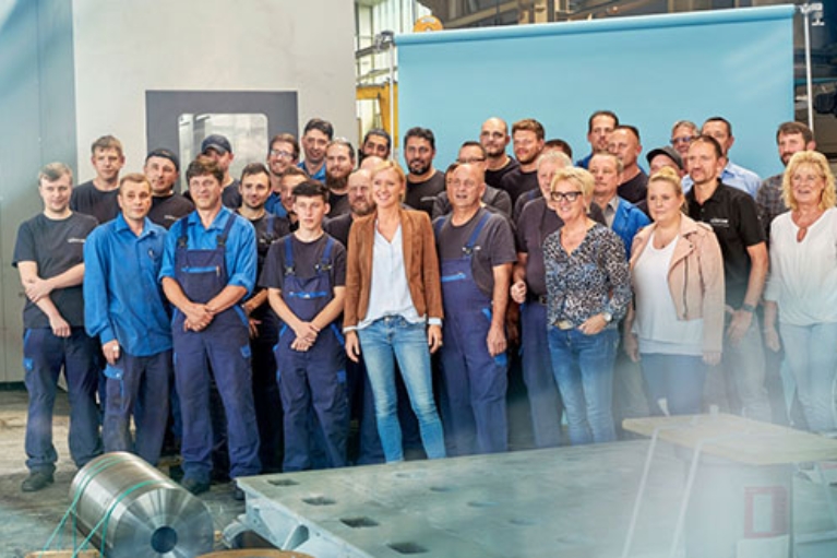 Gruppenbild der Belegschaft der Firma Baum Zerspanungstechnik in einer Werkshalle, rund 35 Personen
