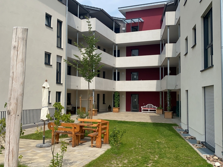 Blick in den Innenhof eines Wohnquartiers mit Rasenfläche und einer Sitzgruppe