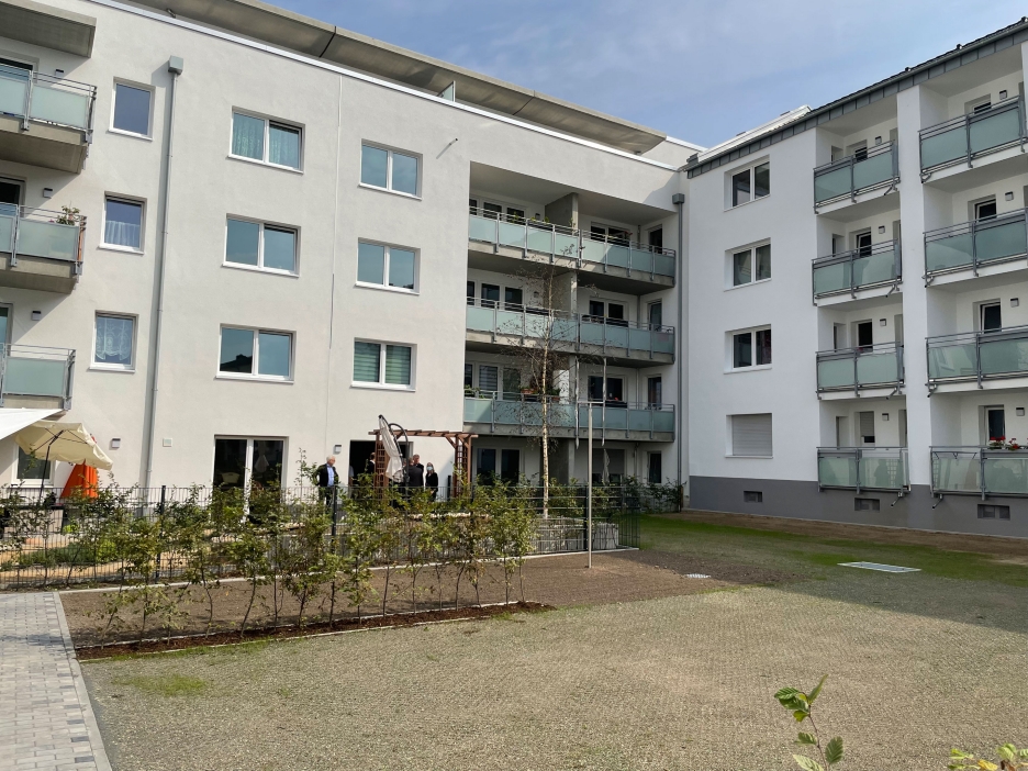 Innenhof eines Wohnblocks mit einer lichten Hecke und einer Parkfläche